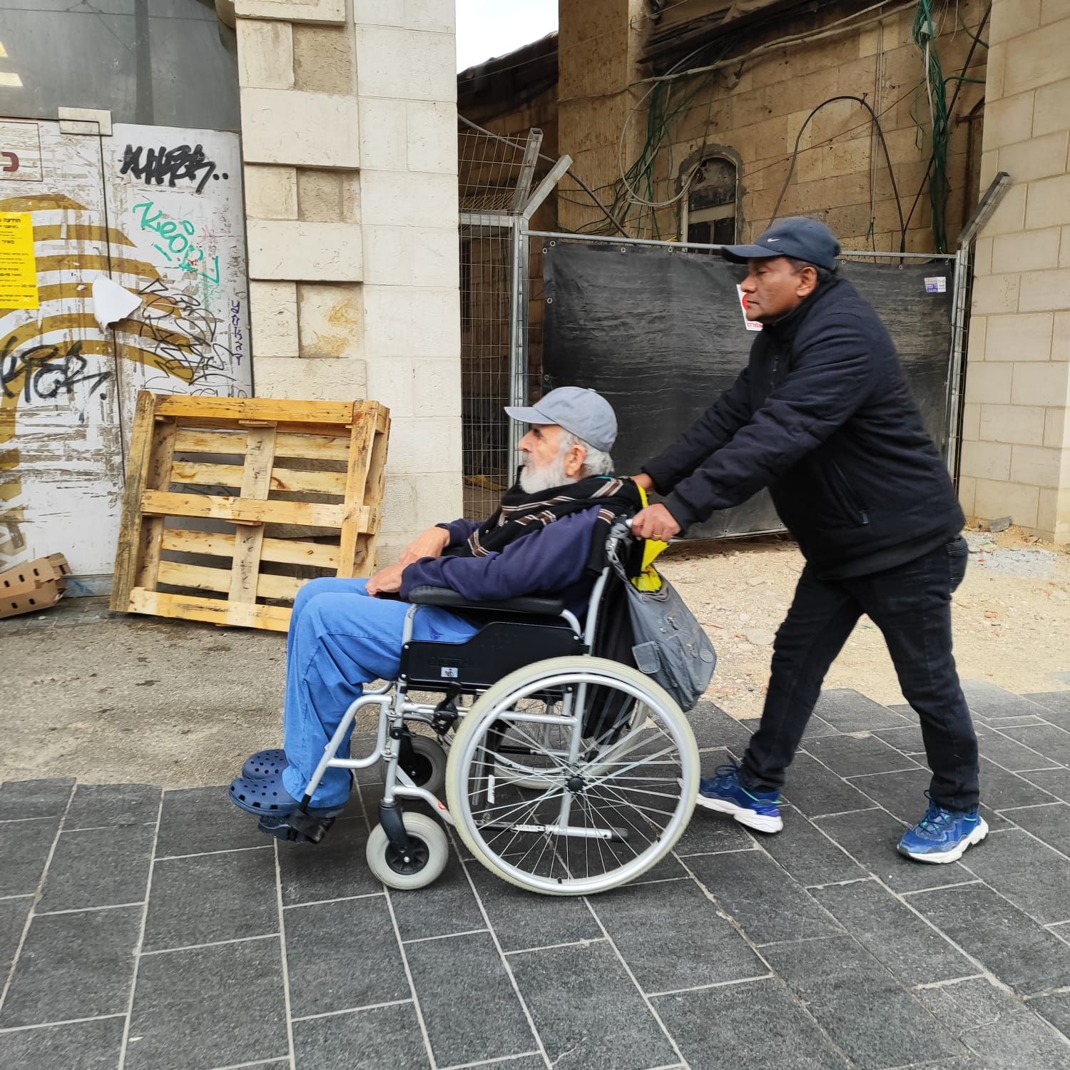 Hombre en silla de ruedas con personal de apoyo. 